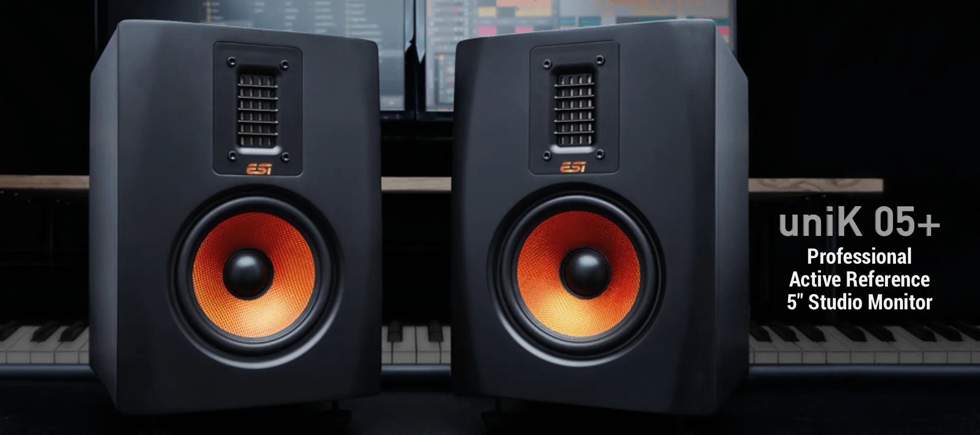 Pair of ESI uniK 05+ studio monitors with distinctive orange woofers, shown at slight angle in professional studio setting