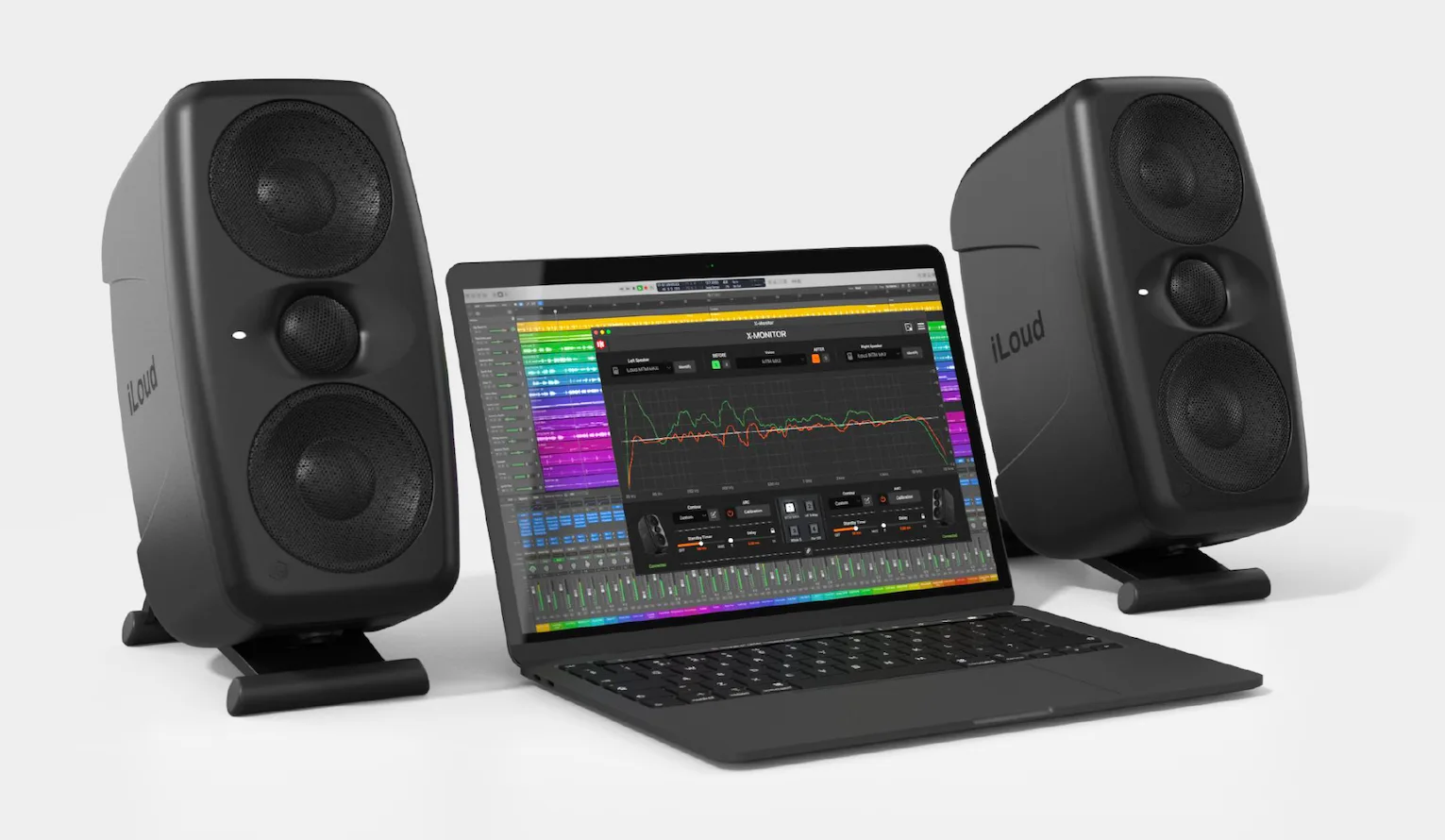 Pair of black iLoud MTM MKII studio monitors flanking laptop displaying music production software on white background