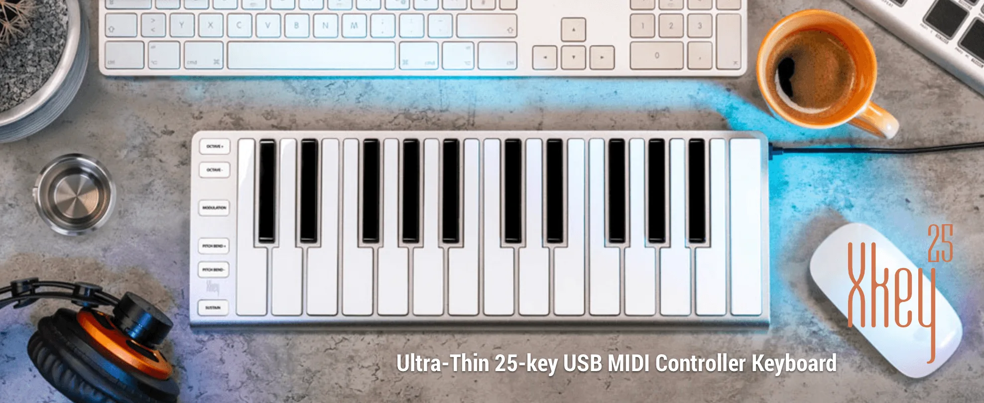 White 25-key USB MIDI keyboard on blue workspace with coffee, headphones, and computer keyboard visible