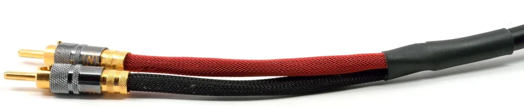 Gold-plated banana connectors on red and black fabric-sleeved speaker cable against white background