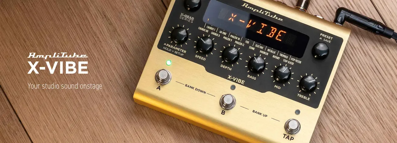 AmpliTube X-VIBE gold and black effects pedal on wooden surface with knobs and footswitches visible