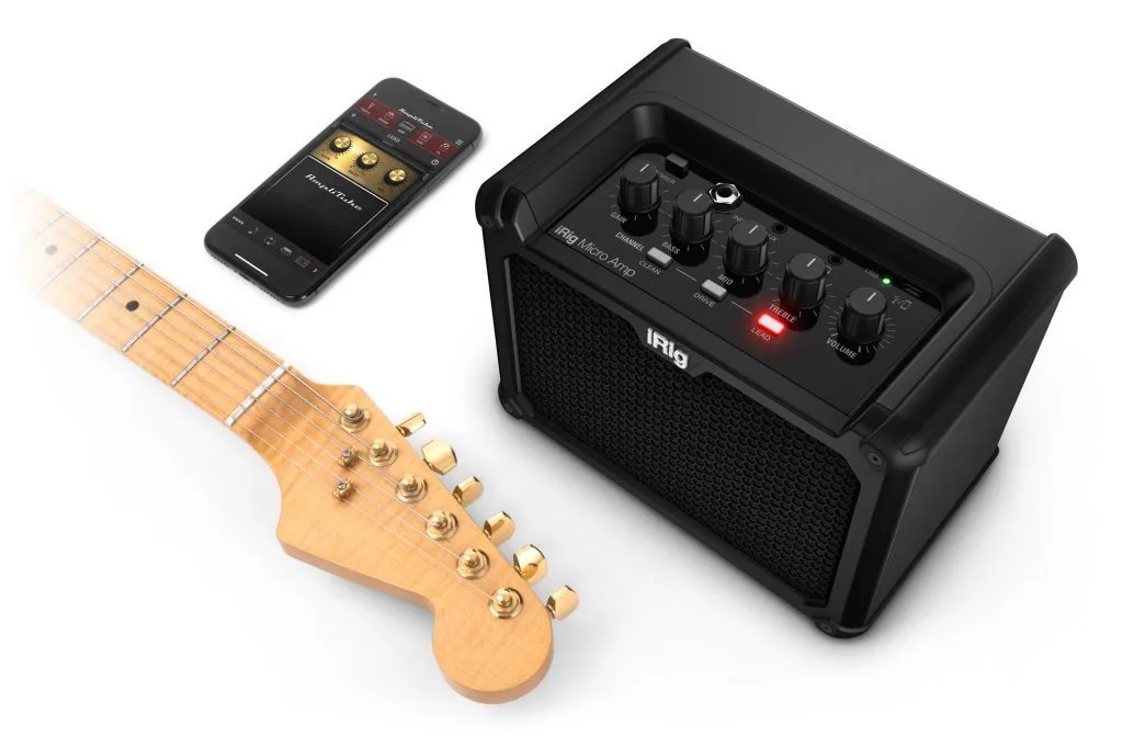 Natural wood electric guitar with maple fretboard beside black iRig Micro Amp and smartphone displaying app interface