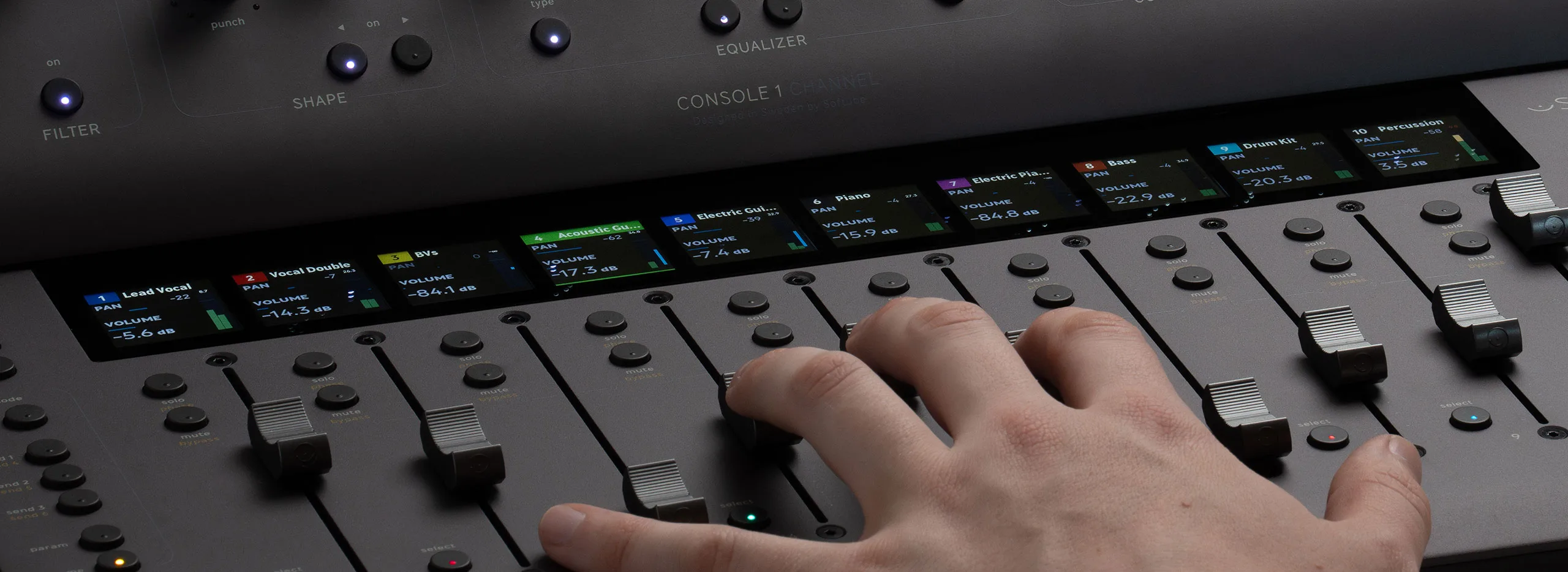 Hand adjusting faders on Console 1 MKIII mixer, showing multiple colored track channels with volume displays