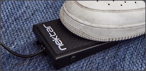 Nektar Impact LX Mini controller with white sneaker on blue fabric, showing black device with cable