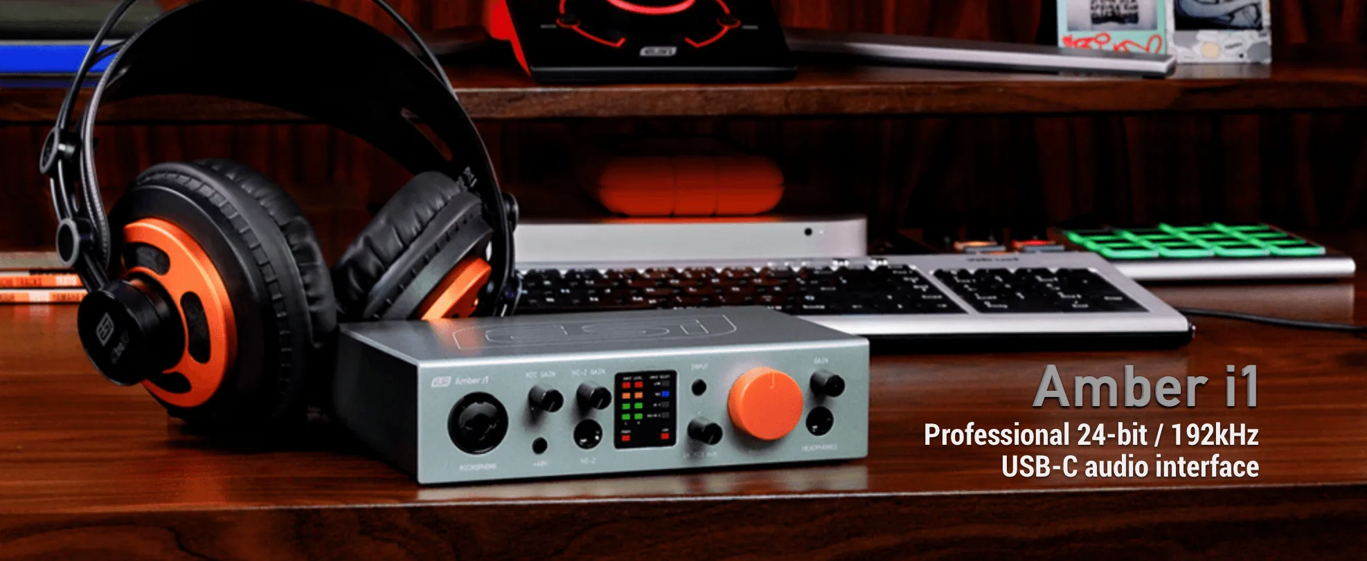 ESI Amber i1 audio interface with orange accents on wooden desk beside black and orange headphones