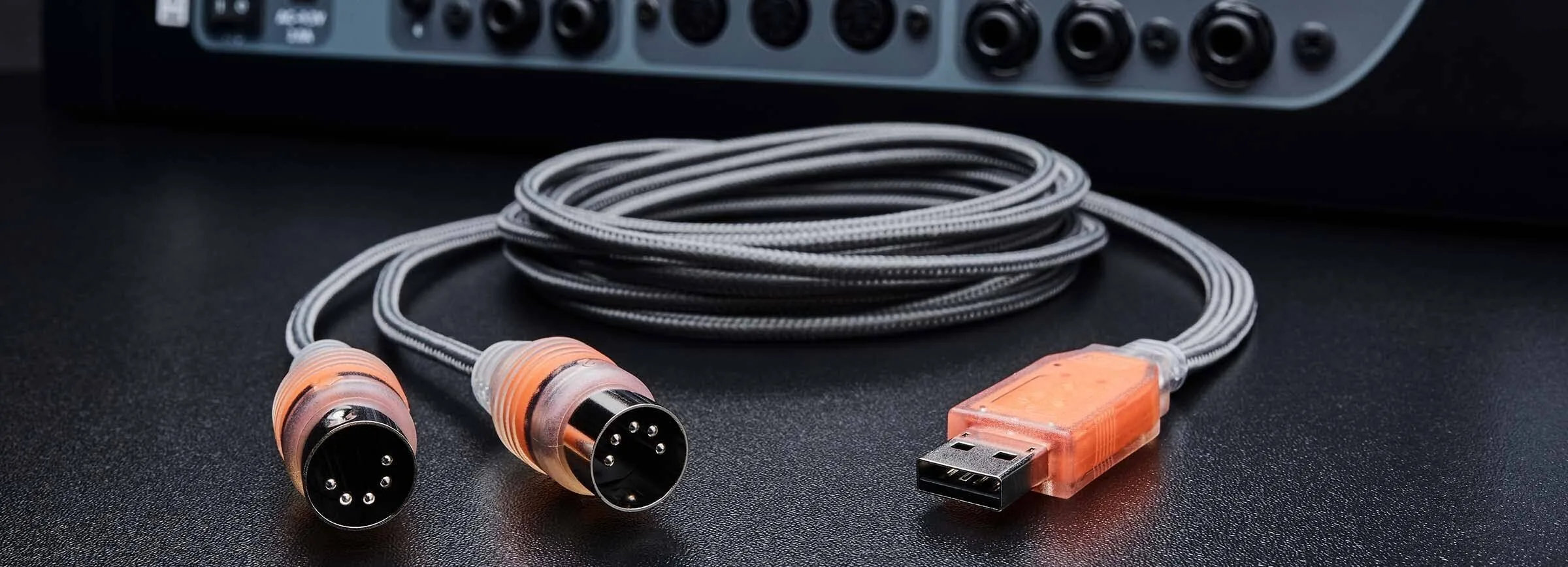 ESI MIDIMATE eX USB MIDI controller with orange connectors and braided cables coiled behind, audio interface visible above