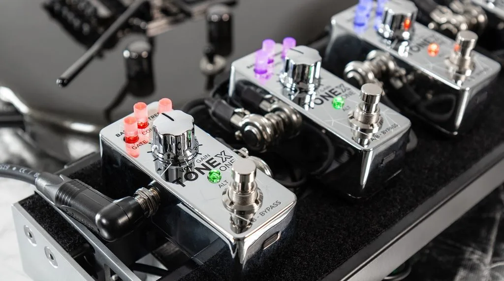 TONEX ONE Joe Satriani pedal with red knobs on black pedalboard alongside other effects units