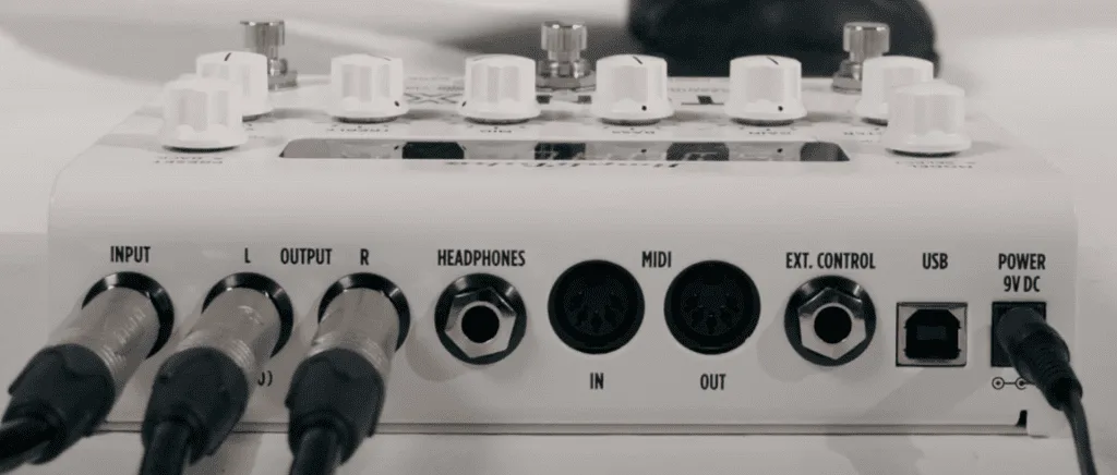 White audio interface pedal front panel showing input/output jacks, headphones port, MIDI connectors, and white knobs arranged horizontally