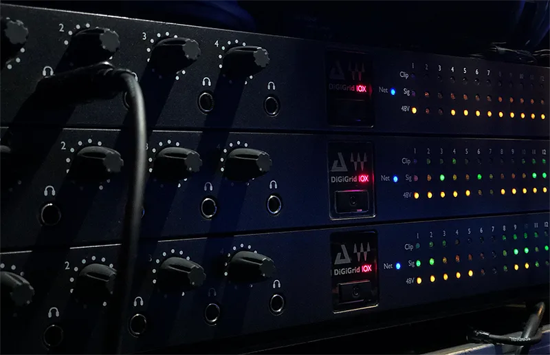 DiGiGrid IOX audio interfaces stacked vertically, showing numbered knobs, headphone outputs, and LED indicator rows illuminated in amber and green