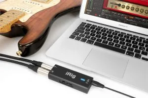 iRig HD2 audio interface connected to MacBook laptop with guitarist's hand visible, showing cable connection setup