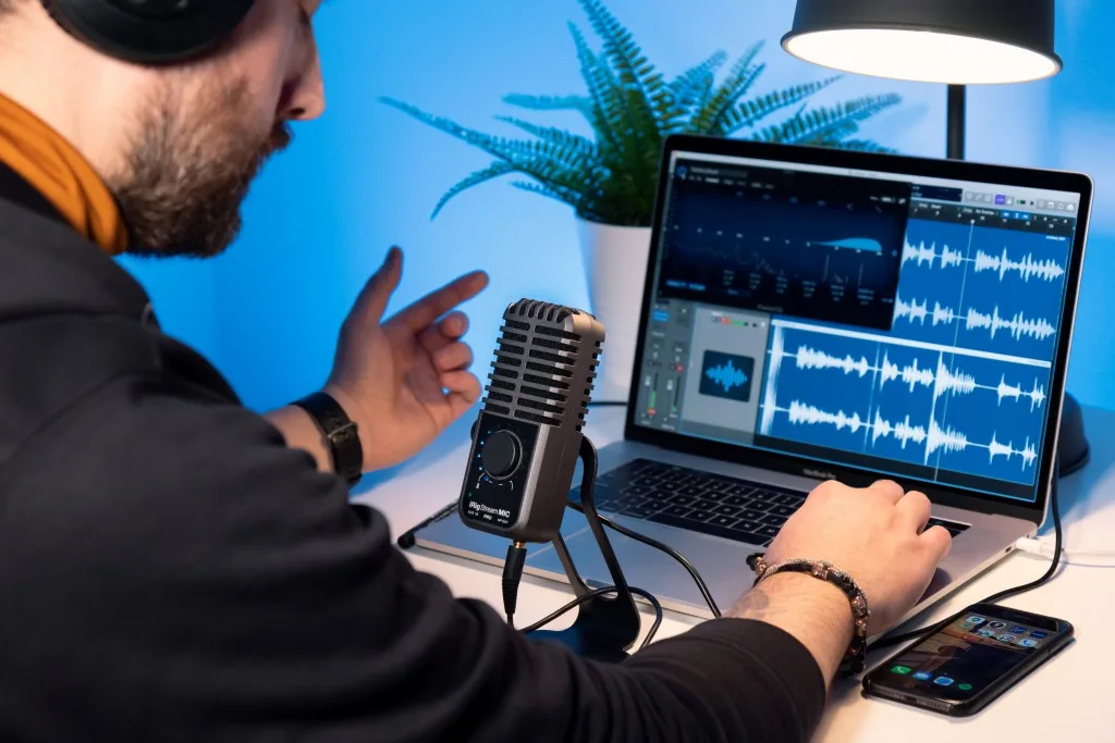 iRig Stream Mic Pro vintage-style microphone positioned in front of laptop displaying audio waveforms in DAW software
