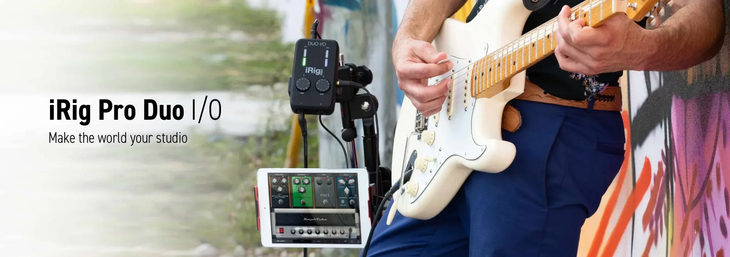 Musician playing white electric guitar outdoors with iRig Pro Duo I/O audio interface and microphone mounted on stand