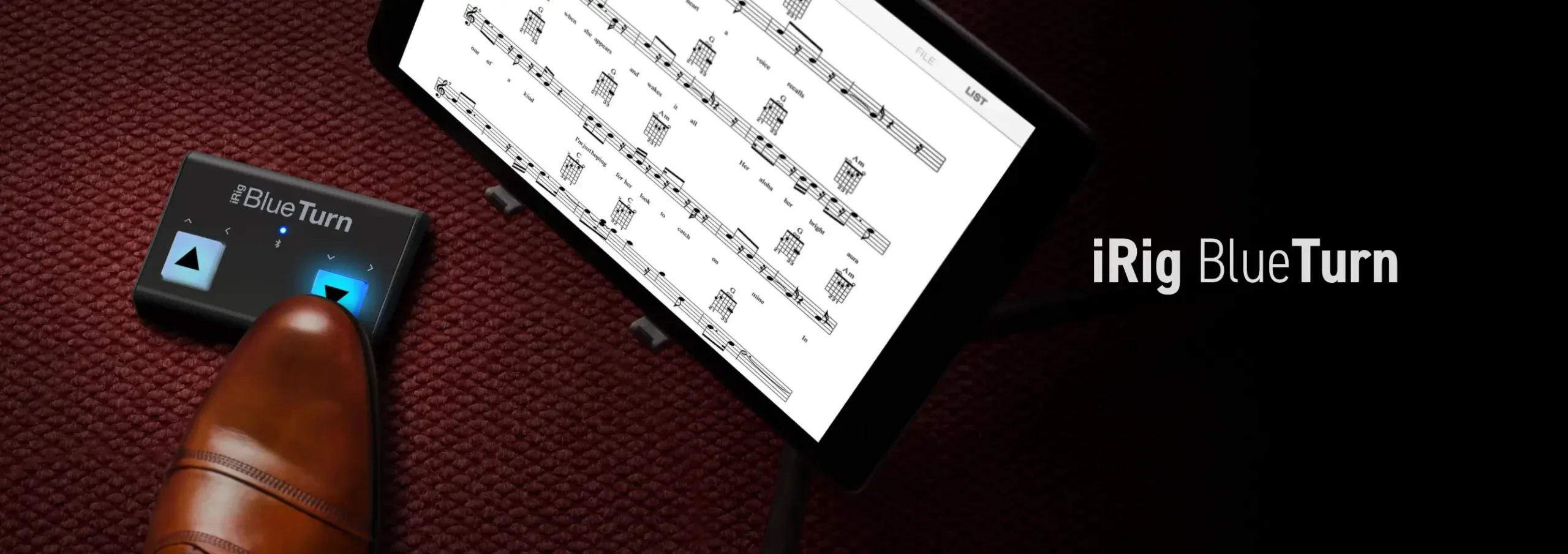 iRig BlueTurn wireless page turner displayed next to sheet music and brown leather shoe on burgundy fabric
