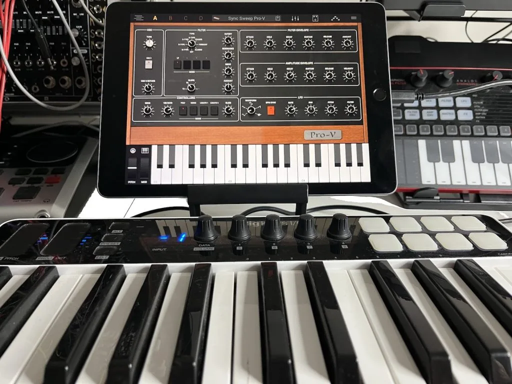iRig Keys I/O 25 keyboard displayed on tablet above physical keys, with Sync Sweep Pro-V synth app visible on screen