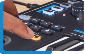 Hands demonstrating finger pad on black Nektar Impact LX Mini keyboard controller with blue accents